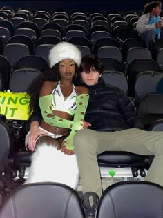 two people sitting on the back of a chair in front of an empty stadium seat