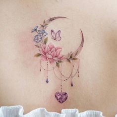 the back of a woman's stomach with flowers, butterflies and a crescent moon