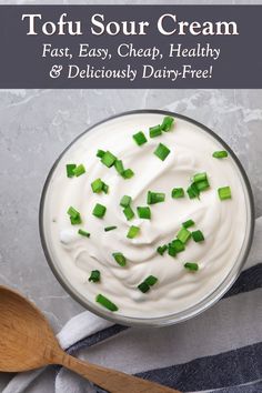 a bowl filled with sour cream and topped with chopped green onions next to a wooden spoon