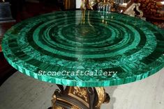 a green marble table sitting on top of a wooden floor next to a gold clock