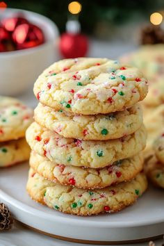 a stack of cookies with sprinkles on a white plate next to a christmas tree