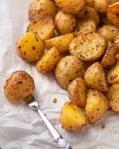 a pile of potatoes sitting on top of a piece of paper next to a fork