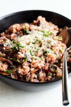 a bowl filled with rice, mushrooms and parmesan cheese on the side next to a spoon