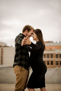 a man and woman dance together on the roof of a building in an urban setting