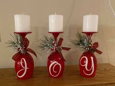 three red vases with white candles on a table