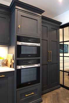 a kitchen with dark gray cabinets and gold trim on the oven, microwave, and stove hood