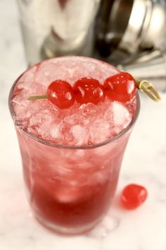 a red drink with ice and cherries on the rim