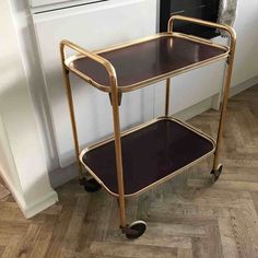 a metal and glass serving cart on wheels