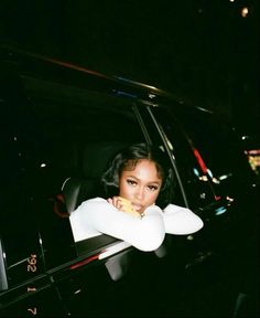 a woman sitting in the back seat of a car with her arms folded out and holding a doughnut