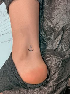 a small anchor tattoo on the side of a woman's lower back ribcage