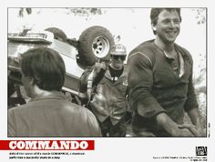 a black and white photo of two men standing next to each other near a car