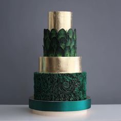 a three tiered cake with green and gold decorations on it's sides, against a gray background