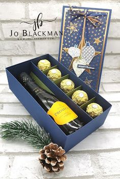 two bottles of champagne in a blue gift box with pine cones and christmas decorations on the side