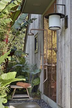 an outdoor shower in the corner of a house with lots of greenery around it