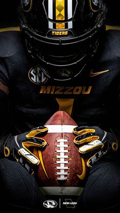 a football player is holding a ball in his hands and wearing a black uniform with yellow accents