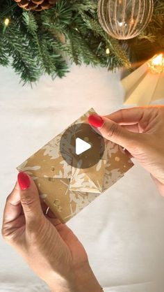 a woman holding a piece of brown paper in front of a christmas tree