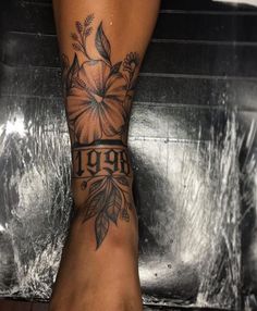 a woman's foot with a flower tattoo on her left leg and the words 1909 written in black ink