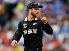 the new zealand player is pointing to his left side while wearing a black hat and jersey