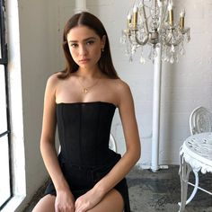 a woman sitting on a chair in front of a chandelier