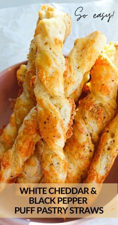 white cheddar and black pepper puff pastry straws in a pink bowl on a table