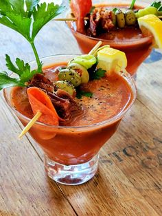 two glasses filled with food on top of a wooden table