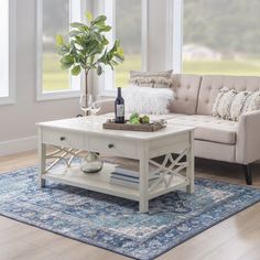 a living room with a couch, coffee table and vase on the rug in front of it