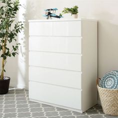 a white dresser sitting next to a potted plant