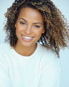 a woman with curly hair smiling at the camera