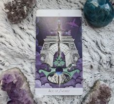 a tarot card sitting on top of a pile of rocks next to some crystals