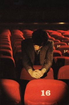 a man sitting in the middle of an empty auditorium with his hand on his knees