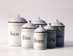 four white canisters with black writing on them are lined up in a row