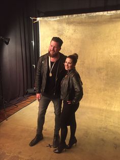 a man standing next to a woman in front of a photo studio backdrop with lights