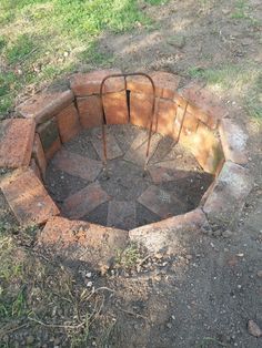 a fire pit made out of bricks in the middle of a field with grass and dirt around it