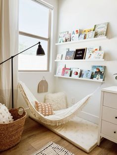 a white hammock in a room with bookshelves on the wall and a window