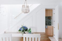 a dining room table with white chairs and blue flowers in the vase on the table