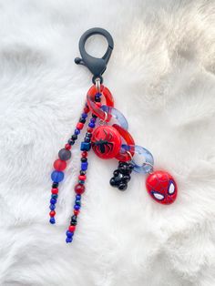 a spiderman beaded keychain hanging from a hook on a white furnishing