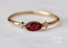 "Don't just rise and shine...rise and shimmer! Our garnet and diamond \"Shimmer\" ring features a marquise rhodolite garnet set on its side and flanked by two sparkling diamonds. A perfect fashion ring, stacking ring or alternative engagement ring! - Rhodolite Garnet measures 6 x 3mm - Side diamonds measure 1.3mm each - Round band measures 1.2mm - Available in 14K yellow, rose or white gold Processing times - Current processing time is 2 - 4 weeks. Each Item is handmade to order with love and ca Red Marquise Diamond Ring Fine Jewelry, Red Marquise Gemstone Ring, Red Marquise Rings With Rose Cut Diamonds, Red Marquise Rose Cut Diamond Rings, Red Marquise Rings With Diamond Accents, Red Marquise Diamond Accent Rings, Red Marquise Ring With Diamond Accents, Red Marquise Cut Rings With Diamond Accents, Red Marquise Rose Cut Diamond Jewelry