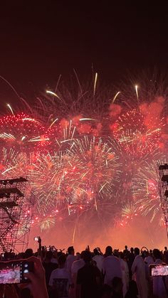 fireworks are lit up in the night sky and people are taking pictures with their cell phones