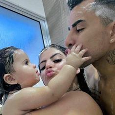 a man and woman are in the bathtub with their child, who is rubbing his face