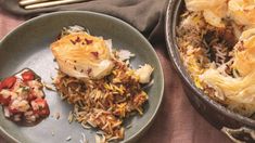 a plate with some food on it next to a bowl filled with rice and vegetables