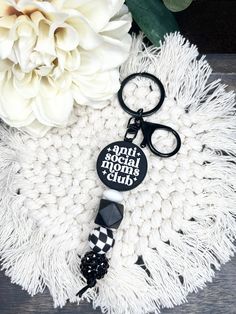 a black and white keychain sitting on top of a table next to a flower