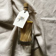 a glass bottle filled with matchsticks on top of a white cloth