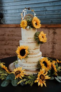 a three tiered cake with sunflowers on top