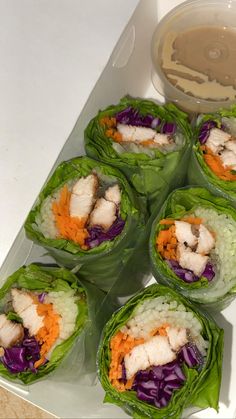 several lettuce wraps with chicken and carrots in them on a white plate