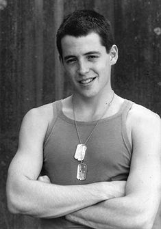 black and white photograph of a young man with his arms crossed wearing a tank top