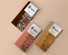 three chocolate bars with designs on them sitting next to each other in front of a beige background