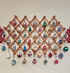 a wooden rack with ornaments hanging from it's sides on a white wall next to a pair of scissors