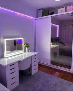 a room with a desk, mirror and lights on the wall above it is lit up by purple lighting