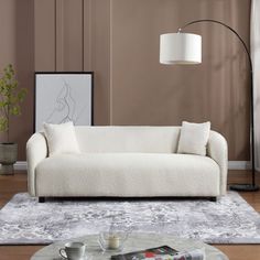 a white couch sitting on top of a wooden floor next to a table and lamp