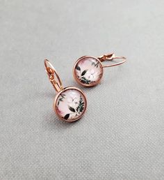 Pretty floral rose gold earrings. Featuring handmade 12mm glass cabochons with a pretty floral print. Set into a rose gold copper setting. Timeless glass dome earrings are an excellent and versatile addition to any jewelry collection. Makes a great gift for her. Please note these earrings aren't waterproof. Please remove before bathing, swimming or showering. D E T A I L S - 12mm in diameter. - 1 inch drop length. - Copper metal leverbacks. - Please note these earrings aren't waterproof. - Please remove before bathing or swimming. ** Due to different monitor settings colour can appear slightly different than the actual item. C A R E ∙ I N F O - Always remove before bed. - Remove prior to showering and swimming. - Keep away from harsh chemicals and oils. - Store with like items. - Keep away